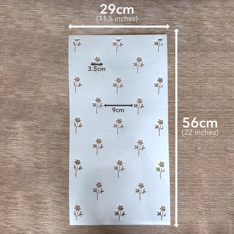 Puede incluir: Una hoja de plantilla rectangular blanca con un patr&oacute;n repetitivo de peque&ntilde;as flores marrones. La hoja mide 29 cm de ancho por 56 cm de alto. Los motivos florales individuales miden 3,5 cm de ancho, con un espacio de 9 cm entre elementos.
