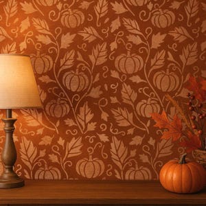 Op de afbeelding: Een warme herfstscène met een bruine lamp, een pompoen en herfstbladeren. De achtergrond is een bruine muur met een herhalend patroon van pompoenen en bladeren. De objecten staan op een houten oppervlak.