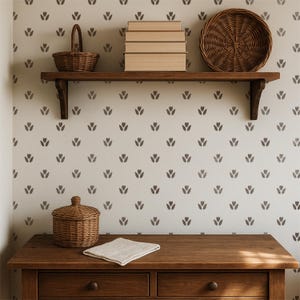 May include: A wooden wall shelf holds a small woven basket, a stack of four beige books, and a round woven tray. Below, a wooden dresser features a lidded woven basket and a folded beige cloth against a wall with a tulip pattern.