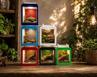 Könnte beinhalten: Ein Stapel aus sechs quadratischen, farbenfrohen Terrariengehäusen mit integrierter LED-Beleuchtung. Die Einheiten haben blaue, weiße, rote, schwarze und grüne Rahmen, die jeweils einen einzigartigen Miniaturlebensraum mit Steinen, Holz, Moos und kleinen Wasserschalen enthalten.