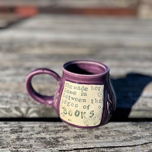 May include: Purple ceramic mug with a white design that reads "She made her home in between the pages of books".