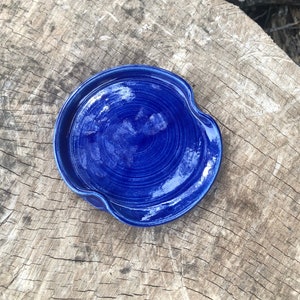 Könnte beinhalten: Eine blaue Keramik-Schale mit einem welligen Rand. Die Schale hat ein Spiralmuster und eine glänzende Oberfläche.