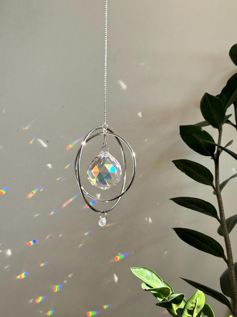 Peut inclure: Un prisme en cristal suspendu &agrave; une cha&icirc;ne argent&eacute;e &agrave; l'int&eacute;rieur d'un double anneau. Le prisme projette des arcs-en-ciel sur le mur.