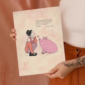 Op de afbeelding: Een print met een illustratie van een vrouw en een varken. De vrouw knielt en kijkt naar het varken met een hart erboven. De print heeft Franse tekst: "L'idée que certaines vies valent moins que d'autres est la racine de tout ce qui va mal dans ce monde."