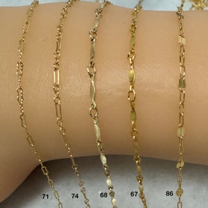 K&ouml;nnte beinhalten: Nahaufnahme von sechs goldenen Ketten in verschiedenen Stilen und L&auml;ngen auf einem Arm. Die Ketten sind mit den Nummern 71, 74, 68, 67 und 86 gekennzeichnet.