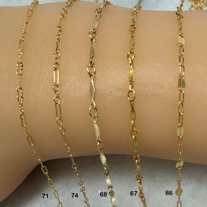 K&ouml;nnte beinhalten: Nahaufnahme von sechs goldenen Ketten in verschiedenen Stilen und L&auml;ngen auf einem Arm. Die Ketten sind mit den Nummern 71, 74, 68, 67 und 86 gekennzeichnet.