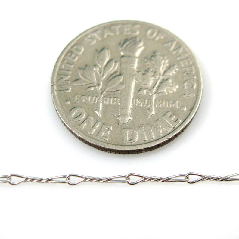 May include: A silver chain necklace with a twisted design. The chain is shown next to a US dime for size comparison.