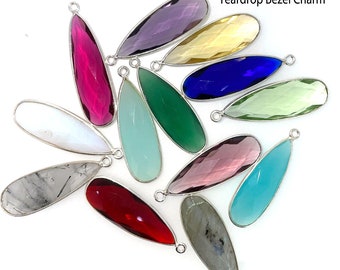 May include: Assortment of 12 faceted elongated teardrop bezel charms in various colors, including white, gray, green, blue, purple, and red. Each charm measures 34mm in length.