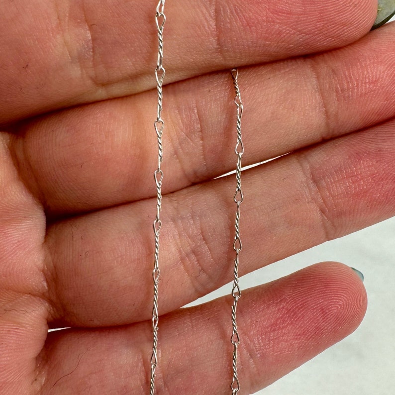 May include: A silver chain necklace with a delicate, twisted design. The chain is approximately 18 inches long.