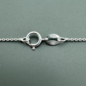 May include: Close-up of a silver chain necklace clasp with a lobster claw closure and a tag that reads "ITALY 925".