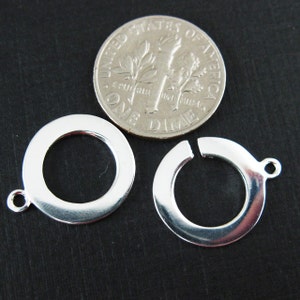 May include: Two silver-toned metal jump rings with a gap for attaching a charm or pendant. The rings are approximately the size of a US dime.