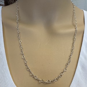 May include: A silver necklace with a heart-shaped chain.