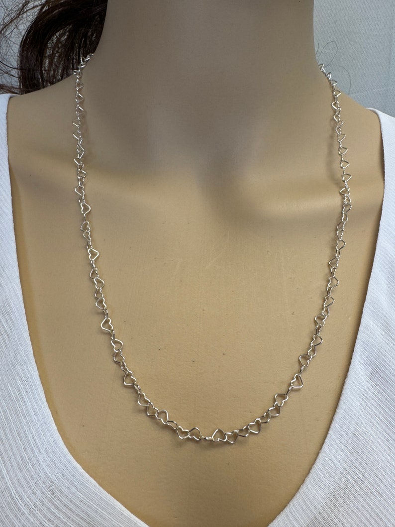 May include: A silver necklace with a heart-shaped chain.