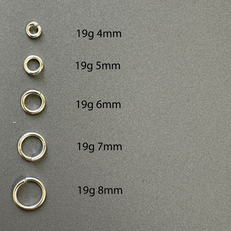 May include: Five silver jump rings of different sizes, from 4mm to 8mm in diameter. Each ring is labeled with its size in millimeters and gauge in grams.