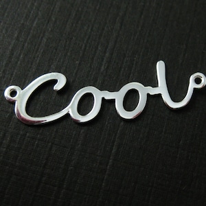 May include: Silver charm with the word "Cool" written in a cursive font.
