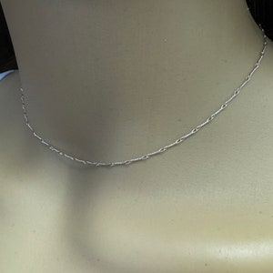 May include: A delicate silver chain necklace with a simple design. The chain is made of small, linked circles.