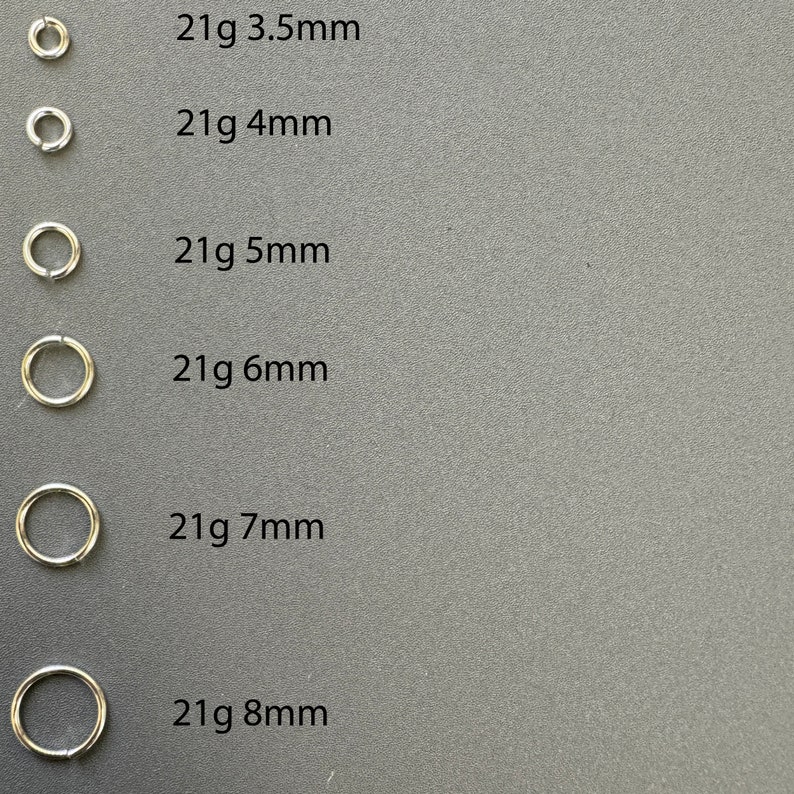 May include: Six silver hoop earrings in different sizes, ranging from 3.5mm to 8mm. Each hoop is labeled with its size in millimeters, for example, "21g 3.5mm".
