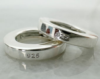 May include: Two silver hoop earrings with a 925 stamp on each. The earrings are simple and elegant.