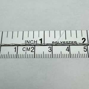 May include: A close-up of a silver chain measured against a ruler. The chain is approximately 1 inch (2.5 cm) long.