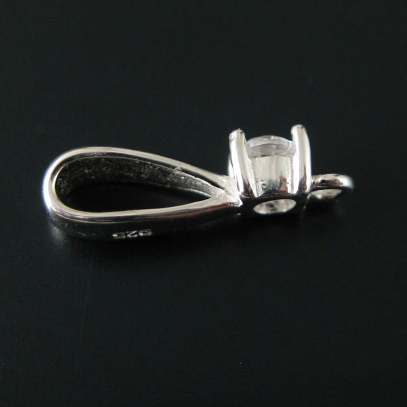 May include: Silver pendant with a clear round stone and a loop for attaching a chain.