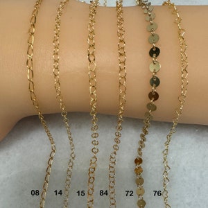K&ouml;nnte beinhalten: Nahaufnahme von sieben goldenen Ketten an einem Arm eines Models. Die Ketten sind in verschiedenen Stilen und St&auml;rken. Die Zahlen 08, 14, 15, 84, 72 und 76 sind am unteren Rand des Bildes sichtbar.