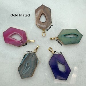 May include: Five gold-plated agate pendants with a hole in the center. The pendants are in the colors pink, brown, green, blue, and purple. The text "Gold Plated" is visible in the top left corner of the image.