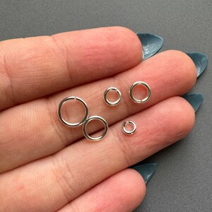 May include: Four silver jump rings of different sizes. The rings are smooth and shiny.