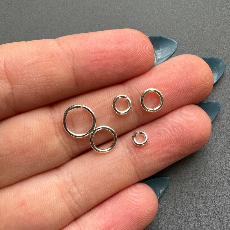 May include: Four silver jump rings of different sizes. The rings are smooth and shiny.