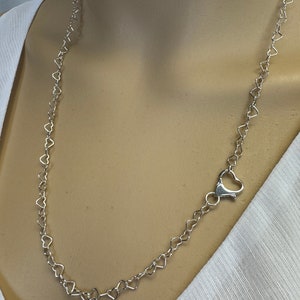 May include: A silver heart-shaped chain necklace with a lobster clasp closure.