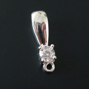 May include: Silver pendant with a clear round gemstone and a loop for attaching a chain.