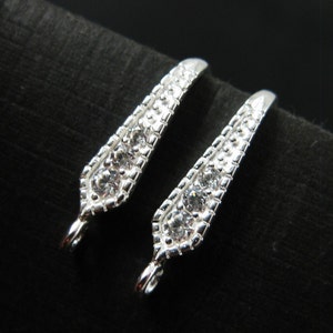 May include: Two silver-toned jewelry clasps with clear crystal accents. Each clasp has a loop on one end and a pointed end with a row of crystals.