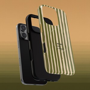 May include: A black smartphone with a black case and a green and white striped phone case. The phone case has the words "Quelques mots d'amour" printed on it.