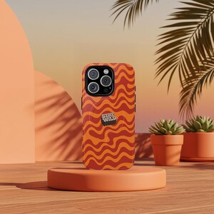 May include: Orange and red phone case with a wavy pattern and the text "Stay Wild" in black. The case is designed for an iPhone.