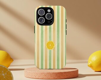 May include: A phone case with a vertical striped pattern in shades of green and tan, featuring a sliced lemon graphic. The case is displayed on a pink, circular stand, with lemons in the background.
