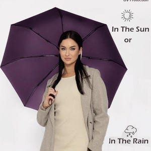 Peut inclure: Une femme tenant un parapluie violet avec le texte "All-round Protection" et "UV Protection" au-dessus du parapluie. Le texte "In The Sun or" et "In The Rain" est sous le parapluie.