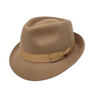 May include: A tan fedora hat with a matching band around the crown. The hat has a classic teardrop crown and a slightly upturned brim. The hat is made of a soft, felt-like material.