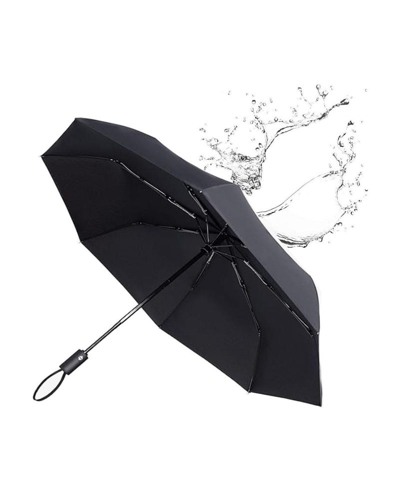 Peut inclure: Un parapluie noir avec une poign&eacute;e argent&eacute;e et un rev&ecirc;tement r&eacute;sistant &agrave; l'eau. Le parapluie est ouvert et la poign&eacute;e est &eacute;tendue. Des gouttelettes d'eau &eacute;claboussent autour du parapluie.