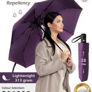 Peut inclure: Un parapluie violet avec une poign&eacute;e noire et une ic&ocirc;ne de plume blanche. Le parapluie est coupe-vent, hydrofuge et offre une protection UV. Il est l&eacute;ger, pesant 313 grammes et se replie &agrave; 28 cm. Le parapluie est pr&eacute;sent&eacute; tenu par une personne portant un manteau beige. Le texte "Satisfaction garantie" et "Excellente qualit&eacute;" est visible sur un sceau dor&eacute;.
