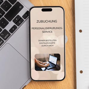 May include: A smartphone displays text in German: "ZUBCHUNG PERSONALISIERUNGS-SERVICE DEINER BESTELLTEN DIGITALEN KARTE DURCH MICH." A small image shows a person using a laptop. The phone rests on a wooden surface next to a laptop and a notepad.
