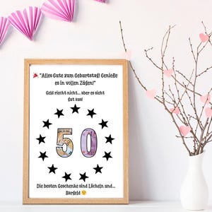May include: A rectangular wooden frame containing a white print with the German text "Alles Gute zum Geburtstag! Genieße es in vollen Zügen!", "Geld riecht nicht... aber es sieht gut aus!", and "Die besten Geschenke sind Lächeln und... Bargeld". The number 50 is centered, surrounded by black stars.