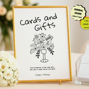 May include: A gold framed sign with the words "Cards and Gifts" in black script. Below the text is a black and white floral illustration. The sign also includes the text "Your presence is the real gift... but just in case, here's the spot!" and the names Isabel + Alfredo.