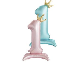 May include: Two foil balloons shaped like the number one, one is pink and one is blue. Each balloon has a gold crown on top.