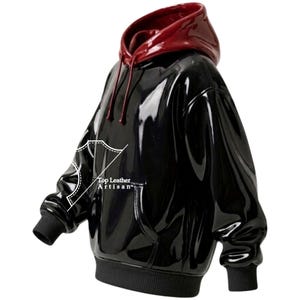 Puede incluir: Una sudadera con capucha negra brillante con capucha y cordones de color burdeos. La sudadera tiene un bolsillo de canguro y puños y dobladillo acanalados. El texto "Top Leather Artisan" está impreso en la parte delantera.