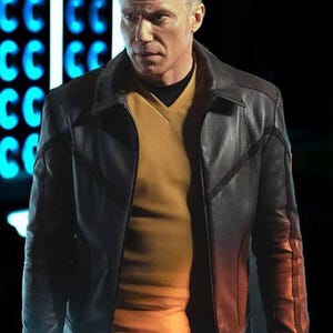 May include: A black leather jacket with a notched collar and a yellow V-neck shirt underneath. The jacket has a quilted design on the shoulders and a zipper closure. The background is dark with blue neon lights.