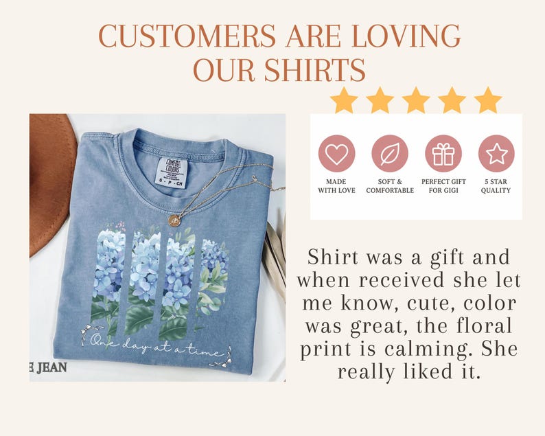 May include: A blue t-shirt featuring a graphic of blue hydrangea flowers arranged in three vertical panels with the text "One day at a time" below. The image includes text stating "CUSTOMERS ARE LOVING OUR SHIRTS" and a five-star review summary.