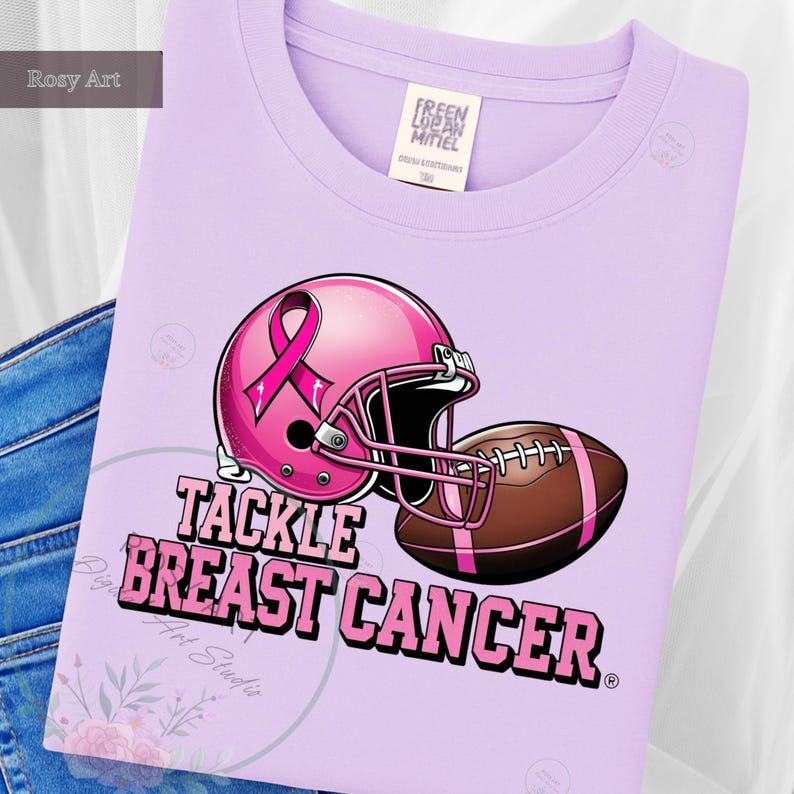 K&ouml;nnte beinhalten: Ein helllila Sweatshirt mit einem rosa Footballhelm und einem braunen Football. Der Helm hat ein rosa Band. Der Text "TACKLE BREAST CANCER" ist darunter aufgedruckt. Das Sweatshirt ist aus weichem Material.