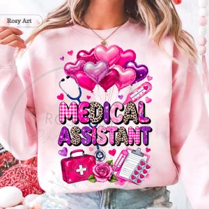 Peut inclure: Sweat-shirt rose clair avec l'inscription "MEDICAL ASSISTANT" dans un m&eacute;lange de motifs et de couleurs. Le motif comprend des ballons en forme de c&oelig;ur, un st&eacute;thoscope, une trousse m&eacute;dicale et un thermom&egrave;tre. De petits c&oelig;urs et une rose compl&egrave;tent le motif.