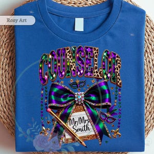May include: Blue t-shirt with a Counselor design. The design features the word "COUNSELOR" in purple, green, and leopard print. A large bow with green and purple stripes, a pencil, and the text "Mr/Mrs Smith" are also included.