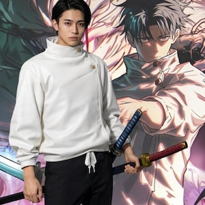 May include: A white sweatshirt with a high collar and asymmetrical button closure. The person is wearing black trousers and holding two swords. A manga-style illustration is in the background.