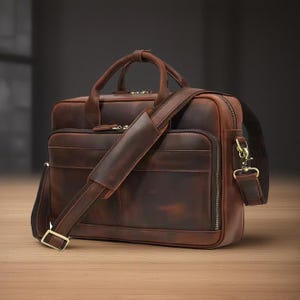 May include: A brown leather briefcase with a long strap and a zippered pocket. The briefcase has a distressed look and is made of high-quality leather.